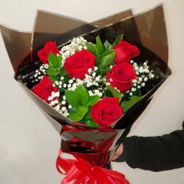 Bouquet of red roses with baby's breath wrapped in dark paper