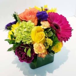 Colorful mixed bouquet in a square green vase