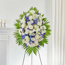 Standing funeral spray of white and purple flowers on an easel