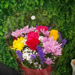 Mixed bouquet of roses and chrysanthemums wrapped in red cellophane with a bow