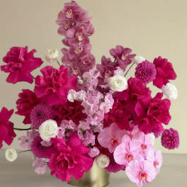 Pink floral arrangement with orchids, dahlias, and ranunculus in a gold vase