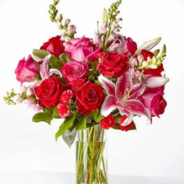 Bouquet of red and pink roses with lilies in a clear glass vase