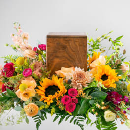 Colorful floral arrangement surrounding a wooden urn box