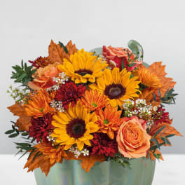 Autumn bouquet of sunflowers, roses, and mums in a pumpkin-shaped vase