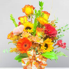 Bouquet of mixed autumn flowers in a glass vase with a patterned ribbon