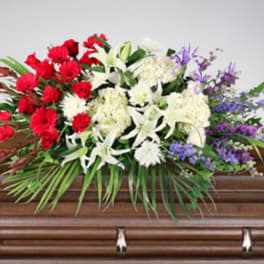 Floral spray of red, white, and purple flowers on a casket