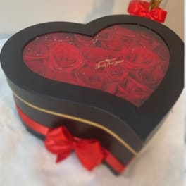 Heart-shaped box filled with red roses and a red ribbon bow