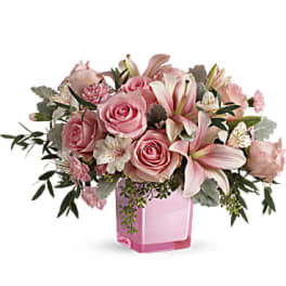 Pink roses and lilies arranged in a pink glass vase