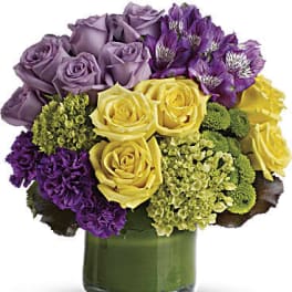 Bouquet of purple and yellow roses in a green glass vase