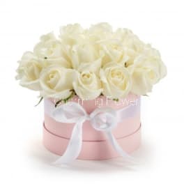White roses arranged in a pink round box with a white ribbon