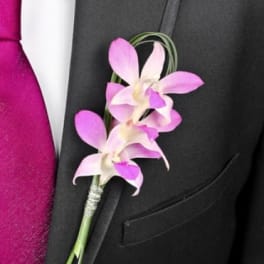 Pink orchid boutonniere pinned to a black suit jacket