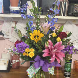 Colorful mixed bouquet in a glass vase with a purple ribbon