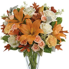 Orange lilies and peach roses in a clear glass vase