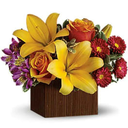 Yellow lilies and orange roses in a wooden cube vase