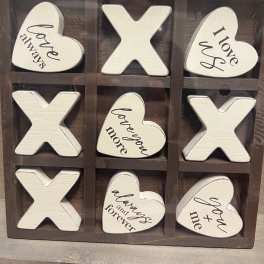Wooden tic-tac-toe sign with heart and X pieces reading love phrases