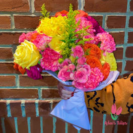 Bright mixed bouquet of roses and carnations wrapped in pale paper