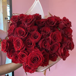 Large bouquet of red roses wrapped in white and tan paper