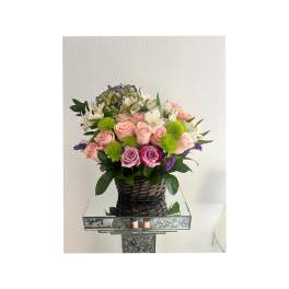 Bouquet of pink roses and white alstroemeria in a woven basket