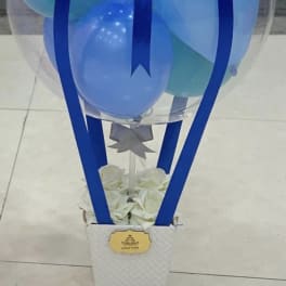 Clear balloon dome with blue balloons and ribbon on a white box