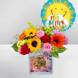 Mixed bouquet in a glass vase with a "Feel Better Soon" balloon