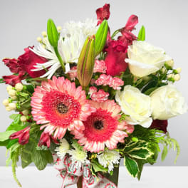 Mixed bouquet of pink gerbera daisies, white roses, and lilies in a vase