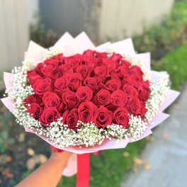 Bouquet of red roses with white baby's breath in pink wrapping