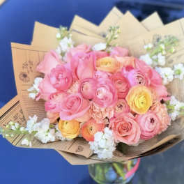 Bouquet of pink and yellow flowers wrapped in brown paper