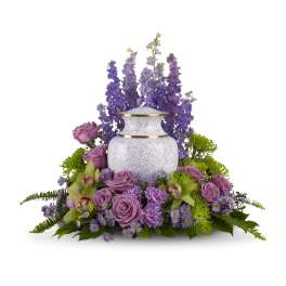 Lavender and green memorial floral ring surrounding a white urn with gold trim