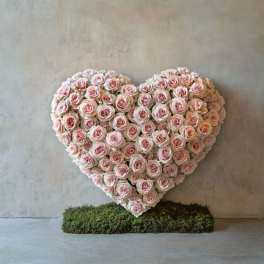 Heart-shaped arrangement of pale pink roses on a moss base