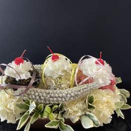Three small floral arrangements with white blooms and ribbon loops on a dark background