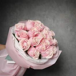 Hand-tied bouquet of light pink roses wrapped in pale pink paper.