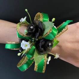 Green ribbon wrist corsage with small black and white flowers