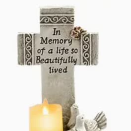 Memorial cross with a candle and dove figurines