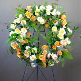 Large floral wreath of peach and white roses on a stand