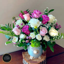 Pink and white rose arrangement in a cute animal ceramic vase with bright green moss hair.