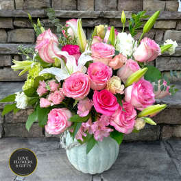 Pink and white roses with lilies in a pale pumpkin-shaped ceramic vase