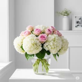 Pink roses and white hydrangeas arranged in a clear glass vase