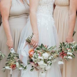 Bride and bridesmaids holding floral bouquets and wreaths