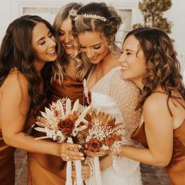 Bridesmaids and bride holding copper-toned bouquets with roses