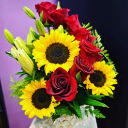 Bouquet of red roses and yellow sunflowers in a decorative vase