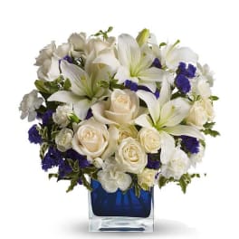 White lilies and cream roses arranged in a blue glass vase