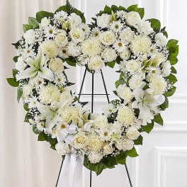 White floral heart wreath on an easel with roses and lilies