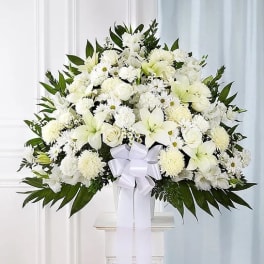 White floral standing arrangement with a ribbon on a pedestal