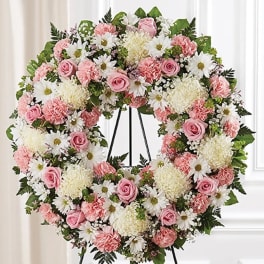 Heart-shaped floral wreath with pink and white flowers on a stand