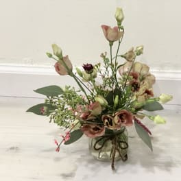Loose pink and cream flowers in a small glass jar