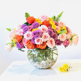 Colorful rose bouquet in a round glass vase with white stones
