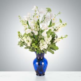 White iris and stock arrangement in a blue glass vase