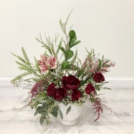 Red and pink floral arrangement in a white vase