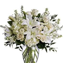 White lilies and roses arranged in a clear glass vase