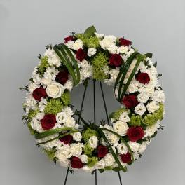 Circular wreath of red, white, and green flowers on a stand